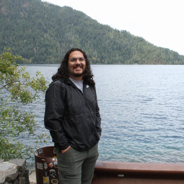 Josh standing by a lake with mountains in the background